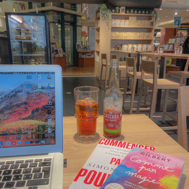 Table avec boisson, livres et ordinateur